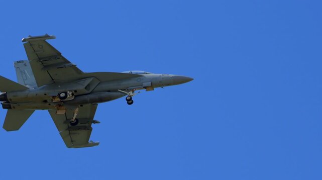 Slow motion close up view of F-18 fighter jets flying beneath the clouds, showcasing military strength, speed, and precision.