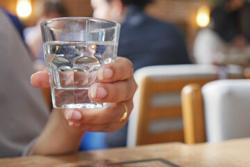 Holding a glass of water in a busy cafe setting
