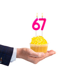 Hand handing a birthday cupcake - Pink candle, number 67 on a white background