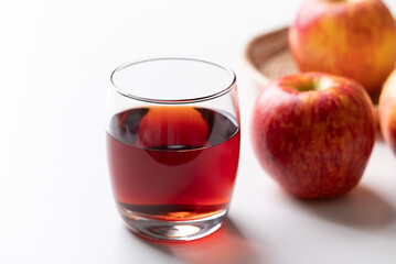 Glass of apple cider with red apple fruit on white background