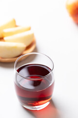 Glass of apple cider with sliced red apple fruit on white background