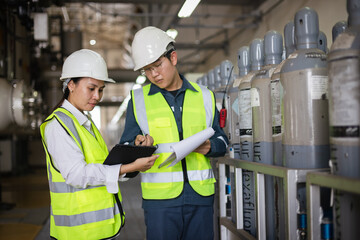 Two engineers inspecting SF6 gas cylinders in industrial facility. Focus on safety management, hazardous material control, compliance documentation, teamwork, and workplace safety audit