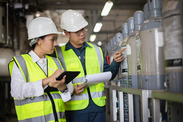 Two engineers inspecting SF6 gas cylinders in industrial facility. Focus on safety management, hazardous material control, compliance documentation, teamwork, and workplace safety audit
