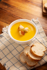 Carrot and pumpkin cream soup. Easy, nutritious and healthy homemade recipe. Served in a white bowl with bread croutons. Perfect to accompany everyday food.