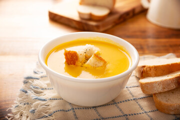Carrot and pumpkin cream soup. Easy, nutritious and healthy homemade recipe. Served in a white bowl with bread croutons. Perfect to accompany everyday food.