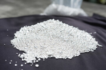 A pile of sparkling pure silver grains, refined to 99.99% perfection, sparkle under the light. Each tiny grain reflects clarity and value.