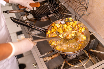 Chef cooking fried potatoes in restaurant kitchen