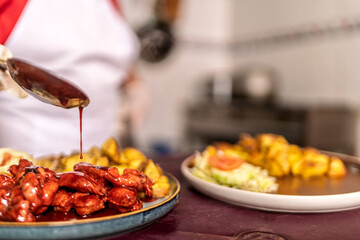 Chef pouring sauce on fried chicken wings