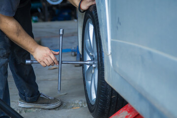 Car mechanic changing tire on a car in auto repair service garage.