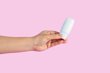 Skin care or sunscreen cosmetic and hand on pink background.