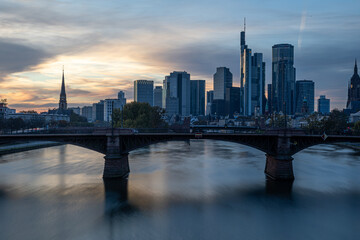 Frankfurt skyline reflecting in main river at sunset with bridge