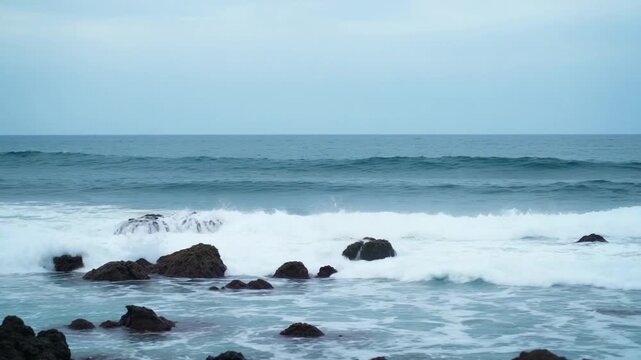 A view of the ocean and waves crashing against the rocky shore with white foam