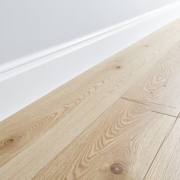 Light-colored wooden floor meets white baseboard