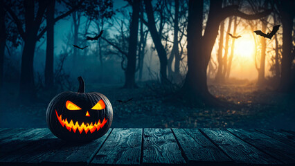 Halloween pumpkin on wooden planks in misty forest with flying bats