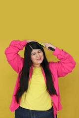 Fototapeta premium 30-year-old Latina woman brushes her long, straight hair, suffering from damaged, dehydrated, and tangled hair