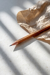 minimalistic still life featuring pencil elegantly placed on rustic kraft paper with bright sunlit stripe