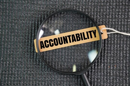 A magnifying glass and a paper tag with the word ACCOUNTABILITY. the acceptance of responsibility for your own actions, decisions, and performance, coupled with the obligation to explain them