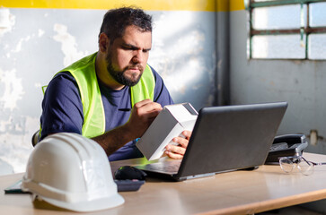 Male worker checking a order package wearing safety gear at industry, factory or warehouse deposit office.