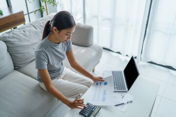 Asian women using calculator calculating Monthly expenses
And Working With Laptop at home