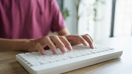 Hands man typing on white keyboard.