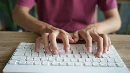 Hands man typing on white keyboard.