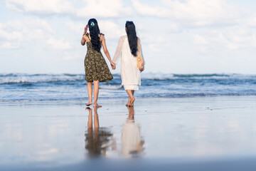 Rear view of two Asian women barefoot on Parangtritis Beach, Yogyakarta