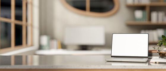 White screen laptop aside books and coffee on marble table across window and computer in living room
