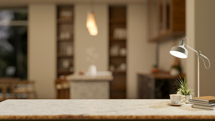 Coffee or tea cup aside books and pot plant under lamp on marble in a modern dining room or kitchen.