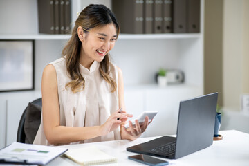 Smiling woman office worker holding using calculator and looking at laptop at white table in office.