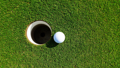 White golf ball green grass putting hole closeup outdoor sport summer competition leisure sunlight top view relaxation accuracy success focus recreation