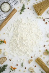 Creative flat lay arrangement of flour, pasta, rolling pin, biscuits, herbs, nuts, and edible flowers on white background for baking, cooking, and culinary presentation with rustic kitchen lifestyle t