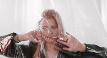 A beautiful woman looks through plastic covering her face.