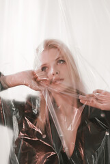 A beautiful woman looks through plastic covering her face.