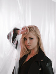 Beautiful woman in black leather jacket on plastic background.