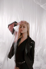 Beautiful woman in black leather jacket on plastic background.