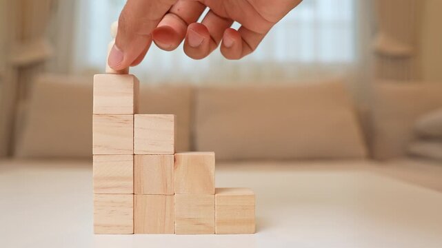 A male wooden figure climbs block steps to the top, symbolizing career advancement, ambition, perseverance, reaching goals, personal growth, leadership, and overcoming obstacles to success.

