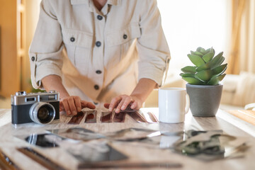 Woman's hands carefully selecting individual film negatives, reviewing old memories and preparing...