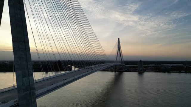 Pullback shot of Gordie Howe International Bridge. Features US shoreline with sun setting in the background.