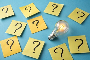 A light bulb surrounded by yellow sticky notes with question marks, symbolizing brainstorming and ideas