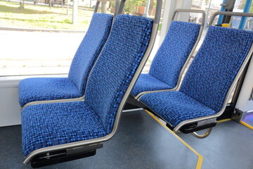 Blue passenger seats on a public tram. An empty tram car with empty seats. Tram seats in an empty car.