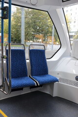 Blue passenger seats on a public tram. An empty tram car with empty seats. Tram seats in an empty car.