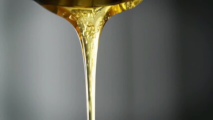 Macro photograph of pure organic golden honey pouring in a thick, sweet stream, highlighting its viscous flow and rich amber color - Powered by Adobe