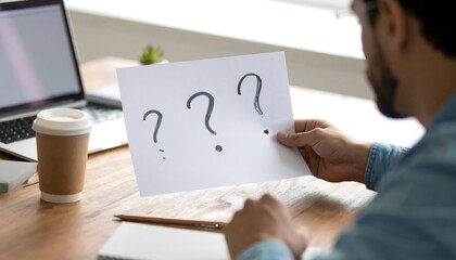 Person holds paper with question marks, pondering solutions