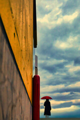 曇天を眺める赤い傘の女性