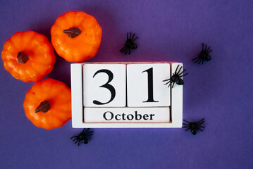 Spooky Halloween composition with pumpkins, spiders and October 31 calendar on purple background. Perfect seasonal design. 