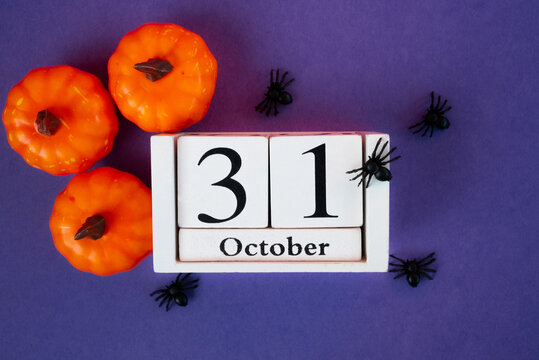 Spooky Halloween composition with pumpkins, spiders and October 31 calendar on purple background. Perfect seasonal design. 