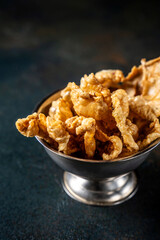 Crispy fried chicken skin in a metal bowl.