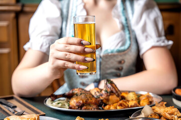 A woman in a dirndl toasting with a glass of beer.