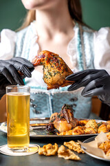 A woman in a dirndl holding a piece of grilled chicken.