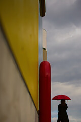 曇り空を眺める赤い傘の女性